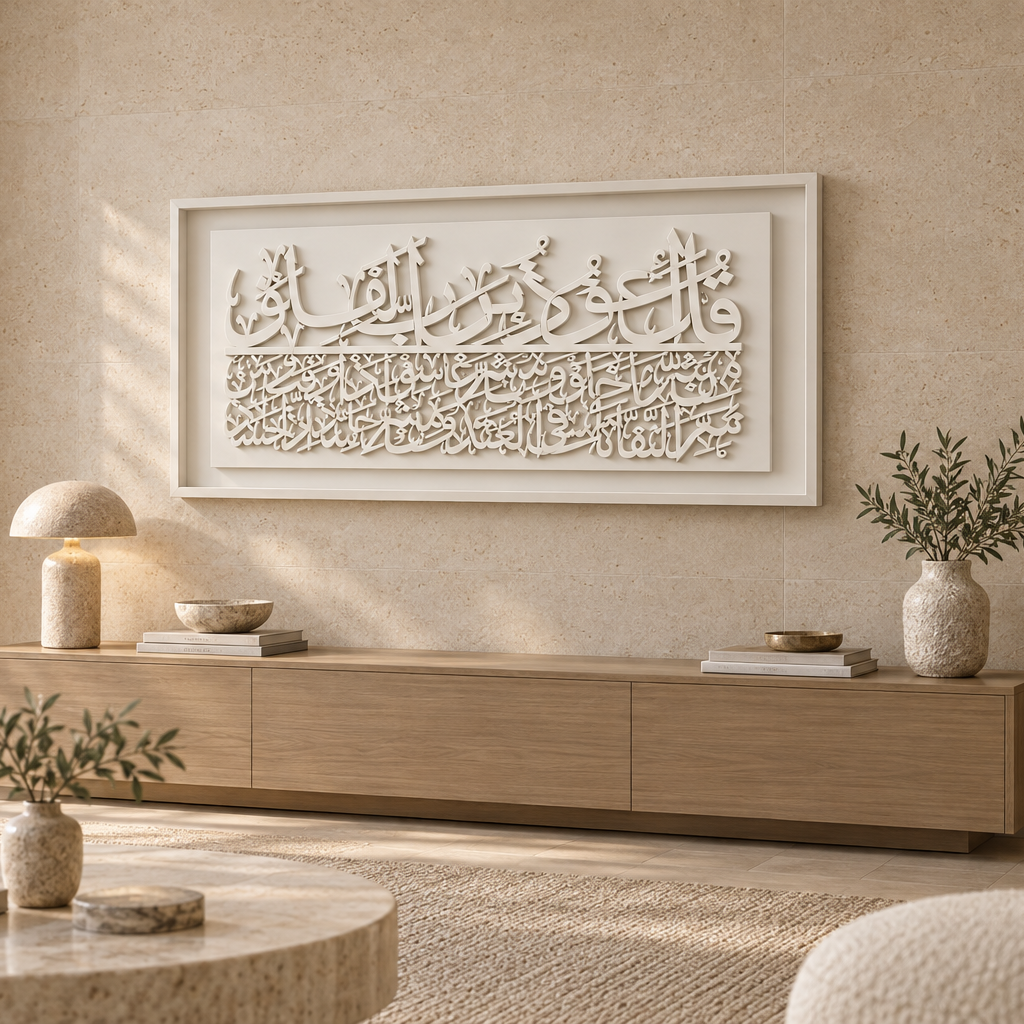 A large white framed Islamic wall art piece featuring Arabic calligraphy Surah Al Fala, displayed in a modern, warm-toned living room above a light wood console table.