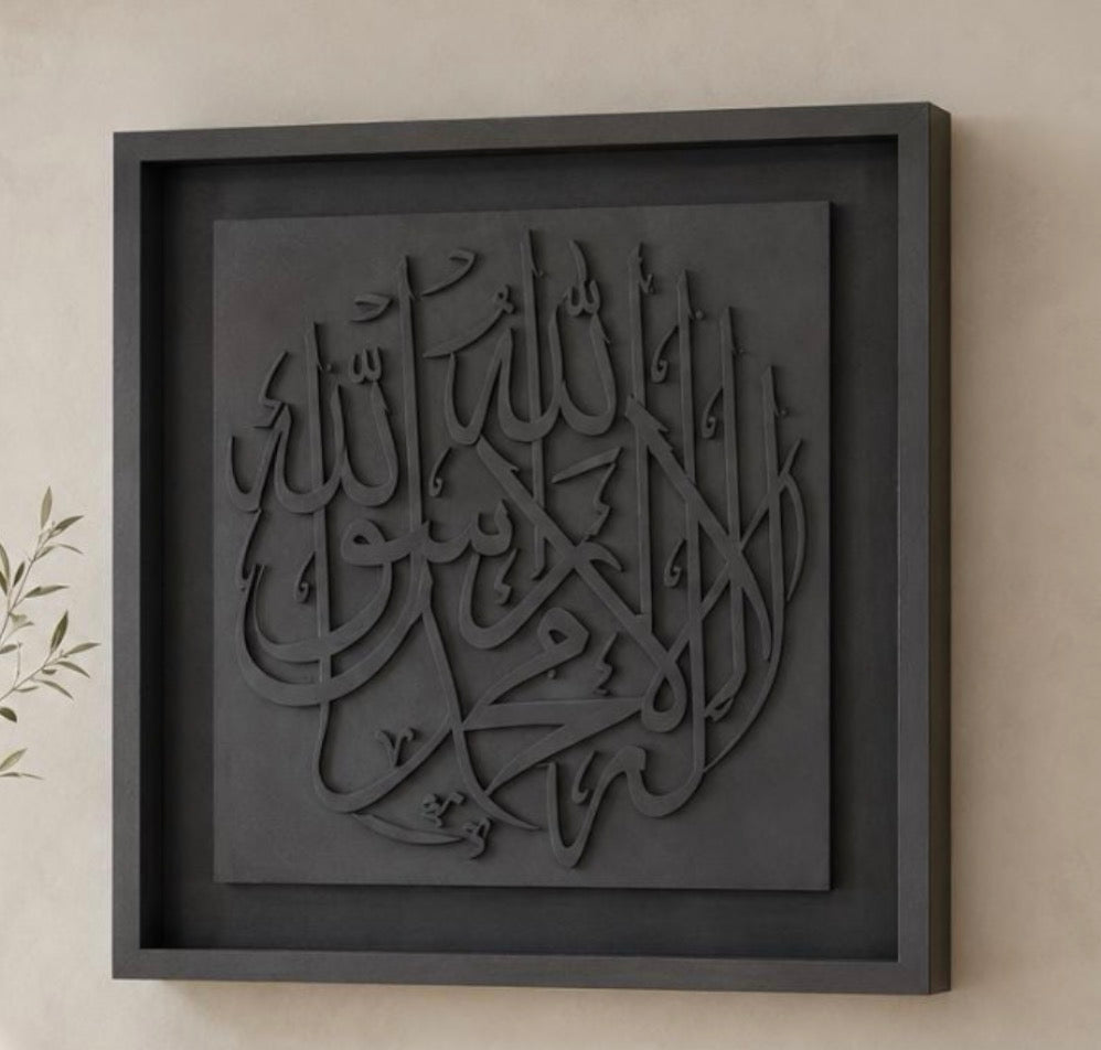Dark charcoal gray framed Islamic wall art featuring 3D raised Arabic calligraphy of 'Allah', mounted on a beige wall.