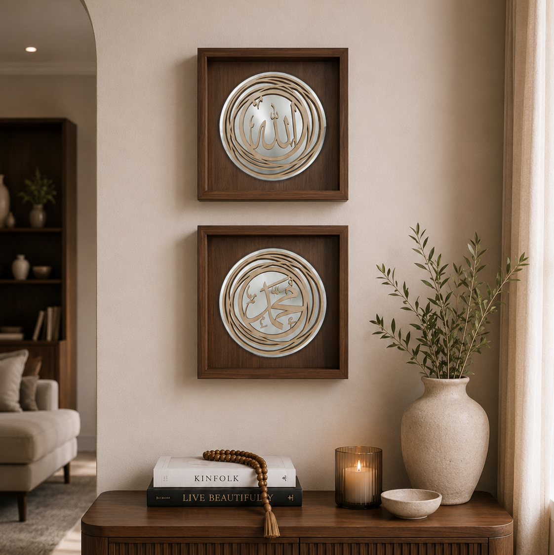 Two square dark wood frames with circular metallic Islamic calligraphy art pieces hanging vertically on a beige wall above a wooden console table with books, a candle, and a vase.